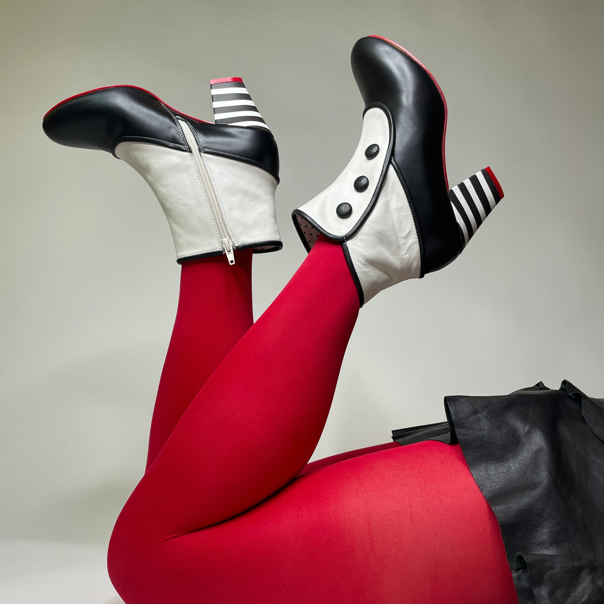 Black and white shoes with red tights on a neutral background