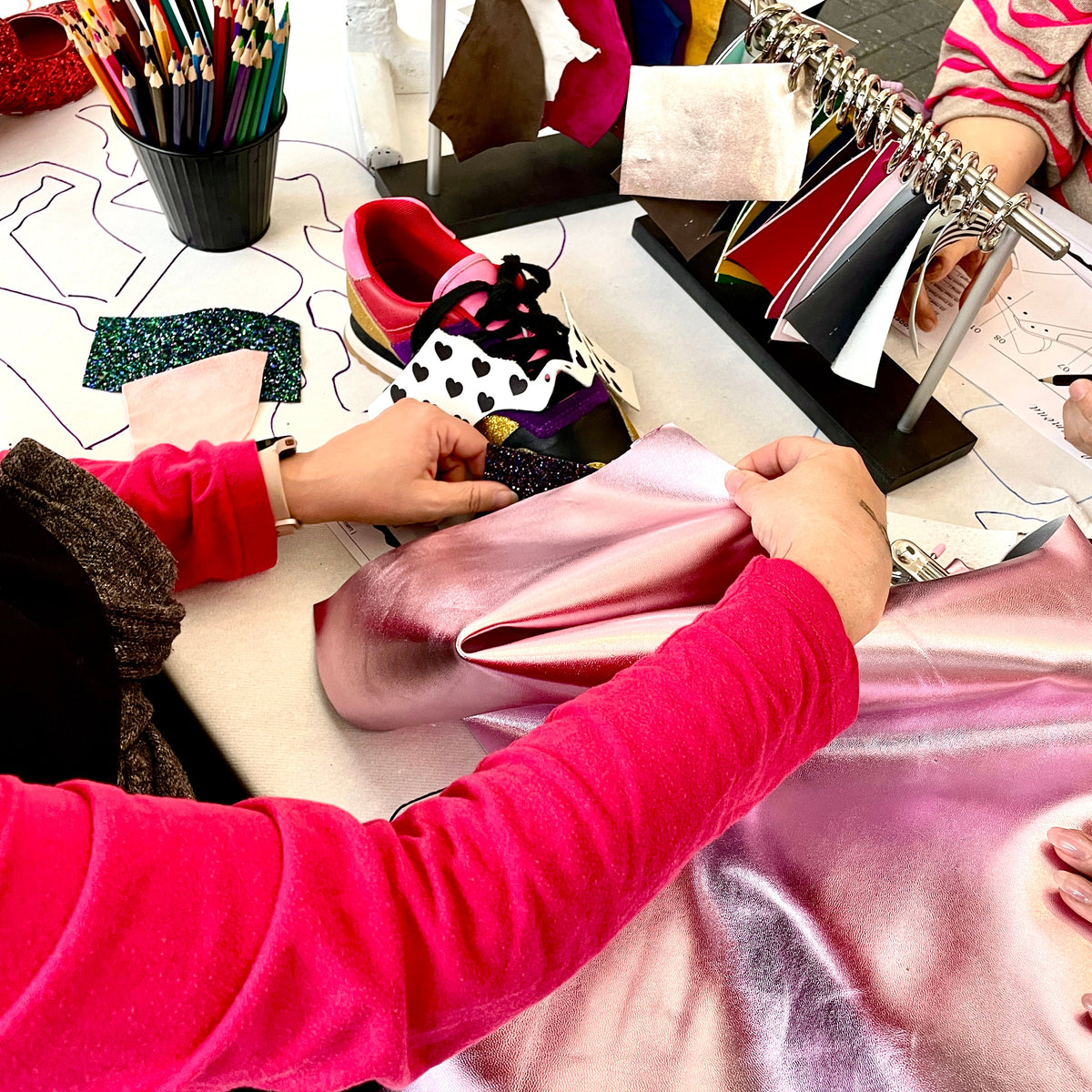 Person working with fabric and shoes at a table in a store setting